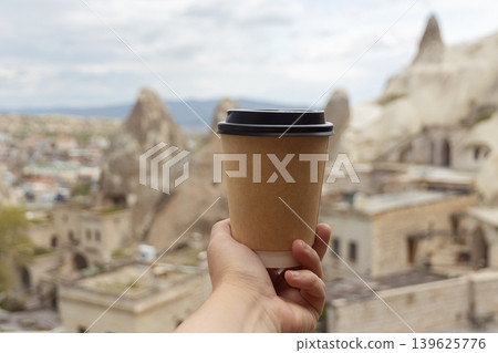 cup of drink in woman's palm against backdrop of mountains in Goreme in Cappadocia, T?rkiye cup of drink in woman's palm against backdrop of mountains in Goreme in Cappadocia, T?rkiye 139625776