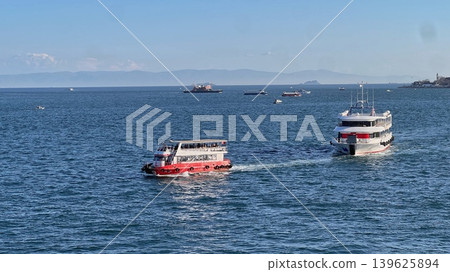 Two boats navigating on a calm sea with distant mountains and a Two boats navigating on a calm sea with distant mountains and a 139625894