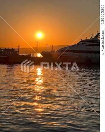 Sunset over water with reflections, silhouette of boats at dock, and distant Sunset over water with reflections, silhouette of boats at dock, and distant 139625895