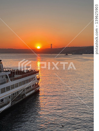 Sunset over the water with a ferry docked at the shore, silhouette 139625903