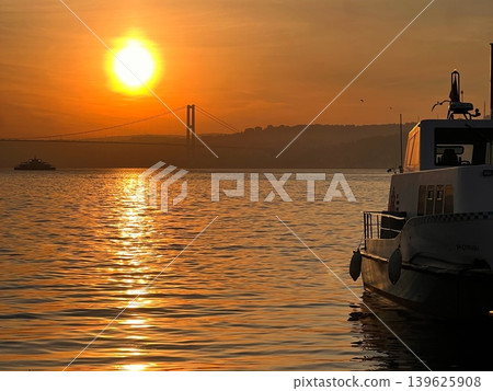 Sunset over water with silhouette of boat and bridge in the background Sunset over water with silhouette of boat and bridge in the background 139625908