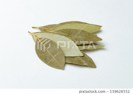 Dried bay leaves arranged in a straight line against a white background. Dried bay leaves arranged in a straight line against a white background. 139626552