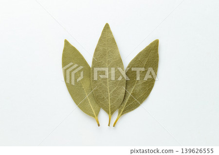A photograph of a fan-shaped dried bay leaf against a white background, taken from directly above. A photograph of a fan-shaped dried bay leaf against a white background, taken from directly above. 139626555