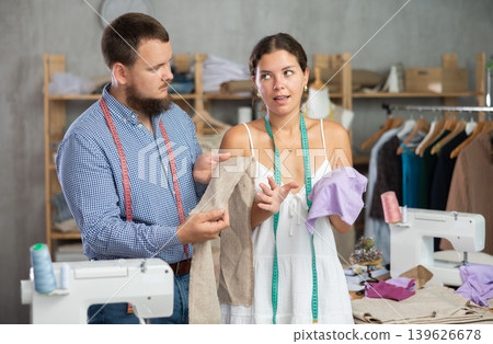 Young female dressmaker discussing textile with man 139626678