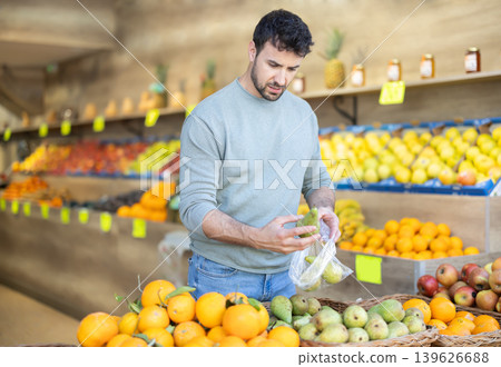 man carefully chooses pears to weigh them before buying man carefully chooses pears to weigh them before buying 139626688
