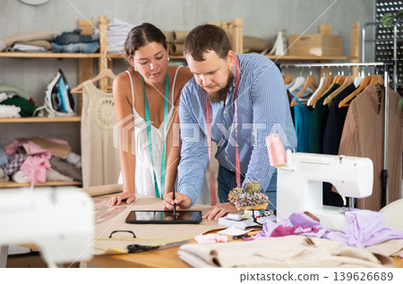 Two young male and female dressmakers drawing on tablet 139626689