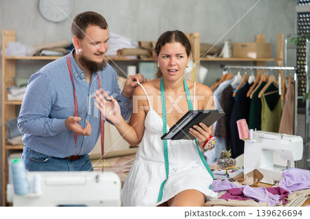Annoyed female dressmaker rejecting coworker flirtation in workshop Annoyed female dressmaker rejecting coworker flirtation in workshop 139626694