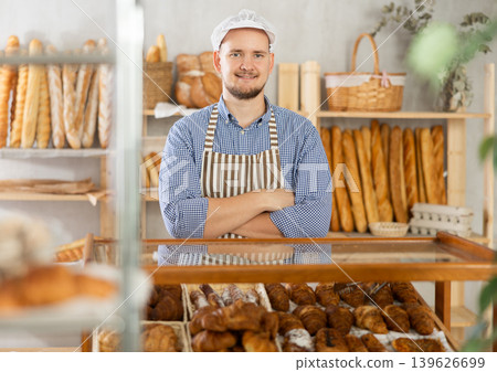 Man seller stands near window with bread and pastries at bakery 139626699