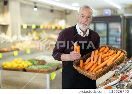 Senior owner of the farm shop offers fresh carrot to customers Senior owner of the farm shop offers fresh carrot to customers 139626700
