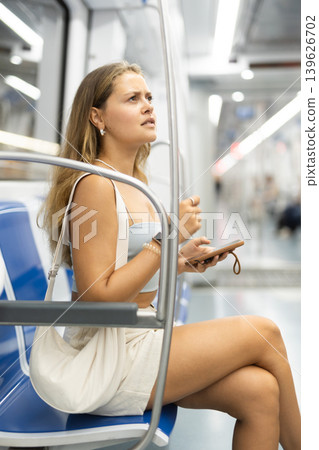 Young girl sitting in wagon holding mobile phone in hand Young girl sitting in wagon holding mobile phone in hand 139626702