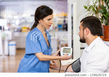 Woman pharmacist measuring man's blood pressure Woman pharmacist measuring man's blood pressure 139626724