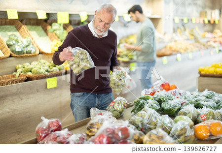 Elderly man choosing artichoke in vegetable shop 139626727