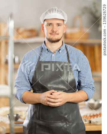 Male baker stands near work table in bakery, resting while working. 139626729