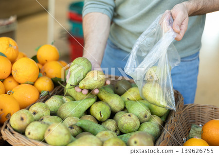 Close-up of male customer's hands taking pears in vegetable shop Close-up of male customer's hands taking pears in vegetable shop 139626755