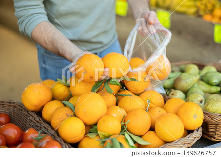 Shopper hands select ripe oranges in supermarket Shopper hands select ripe oranges in supermarket 139626757