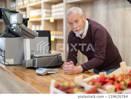 Elderly man standing at cash register counter in eco grocery store 139626764