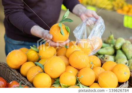Male hands holding orange near the counter of a supermarket Male hands holding orange near the counter of a supermarket 139626784