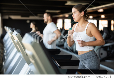 Girl in gym runs with help of treadmill Girl in gym runs with help of treadmill 139626791