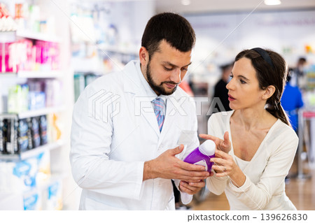 Female buyer consults the pharmacist which lotion or ointment to buy at pharmacy Female buyer consults the pharmacist which lotion or ointment to buy at pharmacy 139626830