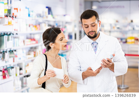 Pharmacist advises customer in pharmacy, offers medicine for body care 139626839