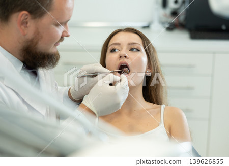 Male doctor checks young woman teeth during visit to dental clinic Male doctor checks young woman teeth during visit to dental clinic 139626855