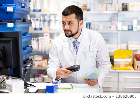 Friendly man pharmacist working at cash desk Friendly man pharmacist working at cash desk 139626903