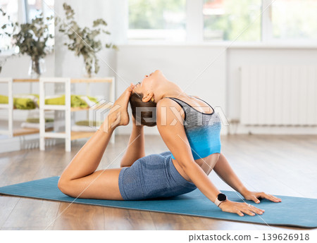 Young female yoga practitioner performing Raja Bhujangasana 139626918