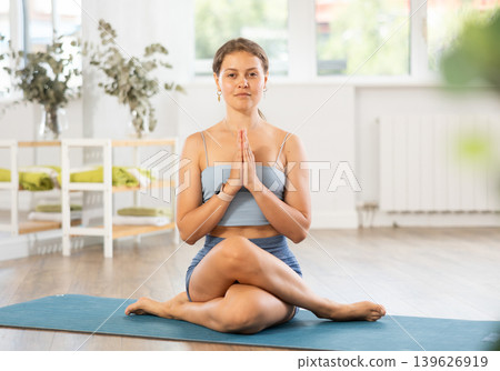 Young woman practicing Gomukhasana with hands in namaste Young woman practicing Gomukhasana with hands in namaste 139626919