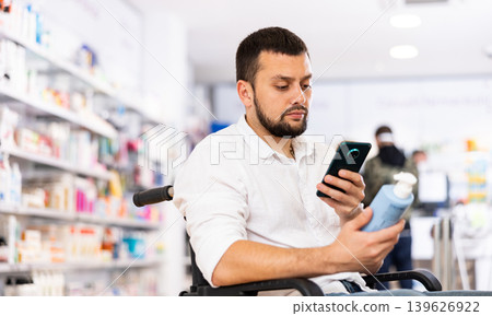 Disabled man photographing medicine product in drugstore Disabled man photographing medicine product in drugstore 139626922