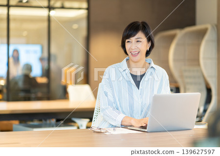 一位中年女性在共享辦公空間使用筆記型電腦工作。 139627597