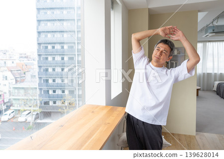 Senior man stretching by the window Senior man stretching by the window 139628014