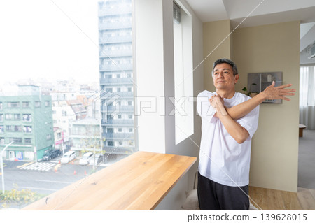 Senior man stretching by the window Senior man stretching by the window 139628015