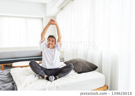 Middle-aged man stretching in bed Middle-aged man stretching in bed 139628018