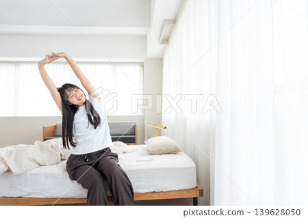 A woman who wakes up in the morning and stretches A woman who wakes up in the morning and stretches 139628050