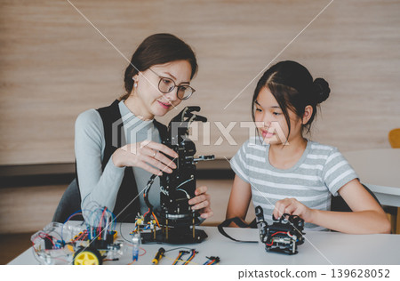 Female Teacher Explaining Robotic Arm Structure to Student in STEM Engineering Workshop Female Teacher Explaining Robotic Arm Structure to Student in STEM Engineering Workshop 139628052