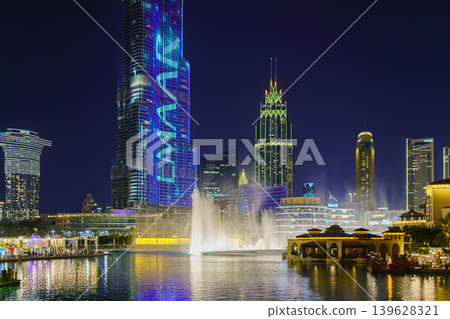 Dubai, United Arab Emirates - Jan 19 2024, panoramic view of the pool with dancing fountains and the Burj Khalifa tower, at nighttime, with illumination and street light, Dubai, UAE Dubai, United Arab Emirates - Jan 19 2024, panoramic view of the pool with dancing fountains and the Burj Khalifa tower, at nighttime, with illumination and street light, Dubai, UAE 139628321