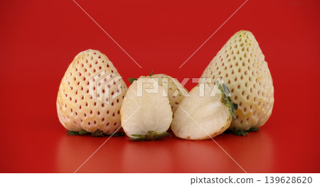 Unique pineberry strawberries, a rare white variety, displayed on a vibrant red background Unique pineberry strawberries, a rare white variety, displayed on a vibrant red background 139628620