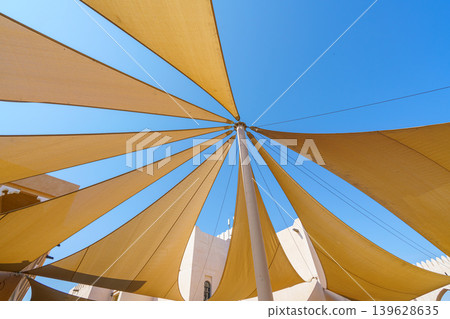 Doha, Qatar- Jan 14 2024, 4k, Bottom-up view of several triangular fabric awnings connected to a pillar in the center, covering the street from sun, Katara cultural village, at daytime, Doha, Qatar Doha, Qatar- Jan 14 2024, 4k, Bottom-up view of several triangular fabric awnings connected to a pillar in the center, covering the street from sun, Katara cultural village, at daytime, Doha, Qatar 139628635