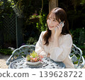 一位女士在花園裡用智慧型手機在家工作。 139628722