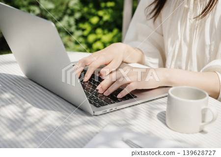 A woman using her laptop outdoors for teleworking. A woman using her laptop outdoors for teleworking. 139628727