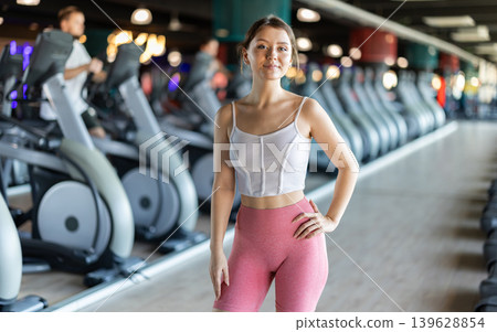 Young woman posing by exercise bike 139628854