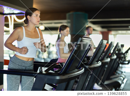 Girl in gym runs with help of treadmill 139628855