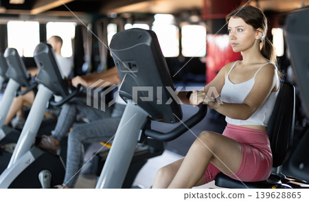 Girl performs exercises with stationary bicycle in gym 139628865