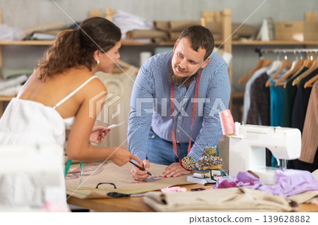 Male and female dressmakers drawing with curves Male and female dressmakers drawing with curves 139628882