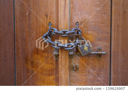 Doha, Qatar Close up view of a vintage lock with chain on a wooden door Doha, Qatar Close up view of a vintage lock with chain on a wooden door 139628907