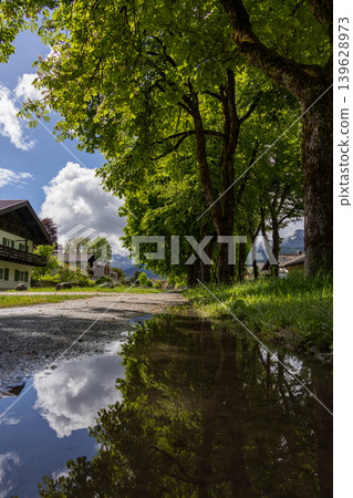 Puddle Reflection of Green Trees and Clouds After Rain in a Bavarian Village Puddle Reflection of Green Trees and Clouds After Rain in a Bavarian Village 139628973