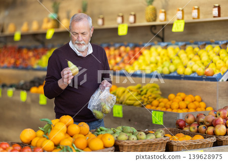 Adult man buyer choosing pears in vegetable shop Adult man buyer choosing pears in vegetable shop 139628975