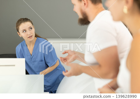 Man stands near the reception and asks questions to the administrator in the dentistry 139628990
