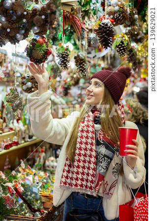 Young woman in souvenir shop examines Christmas handmade toys 139629021