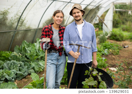 Farmer peasant woman and man works with garden plants in greenhouse Farmer peasant woman and man works with garden plants in greenhouse 139629031